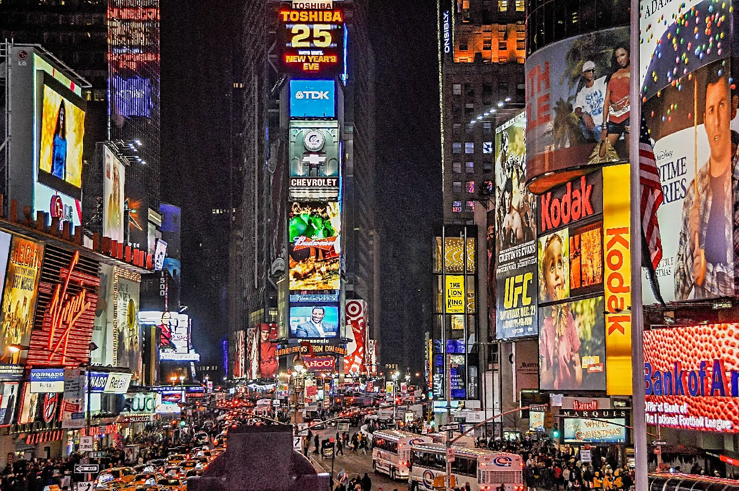 Bright city street with multiple digital signs and video walls at night